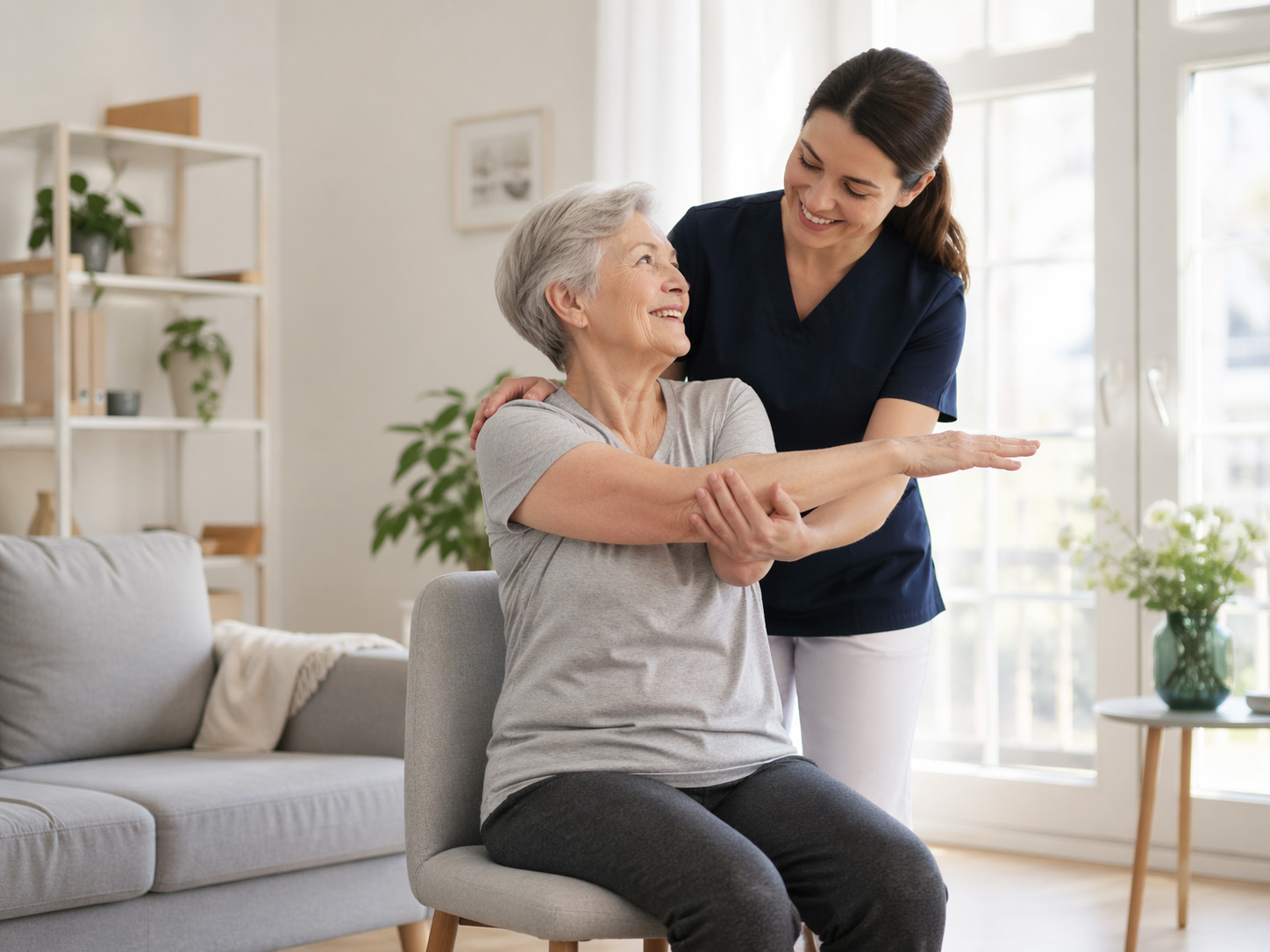 Caregiver helping a senior woman with seated stretching exercises in her living room